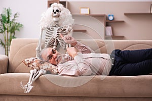 Old man sitting on the sofa with the female skeleton