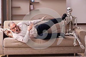 Old man sitting on the sofa with the female skeleton