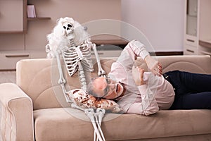 Old man sitting on the sofa with the female skeleton