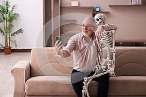 Old man sitting on the sofa with the female skeleton