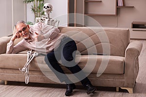 Old man sitting on the sofa with the female skeleton