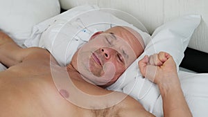 Old man sleeping in bed on white bedding, concept of business trip, travel, sound healthy sleep, problem of insomnia, noise