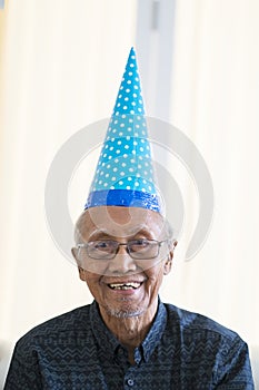 Old man smiling at camera with birthday hat