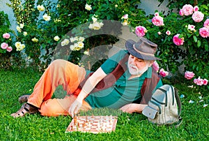 Old man in spring garden with chess. Hobby concept. Happy old age.