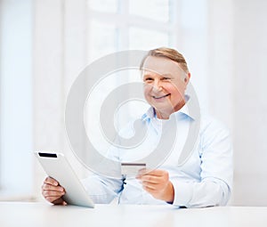 Old man with tablet pc and credit card at home