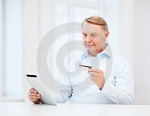 Old man with tablet pc and credit card at home