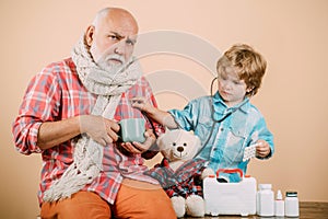 Old man taking a pill. Sick grandfather in a warm scarf around his neck. Happy child and grandfather with stethoscope.