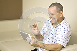 Old man with tattooed hands using tablet PC waving hello having