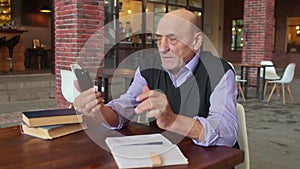 Old man teacher talks with someone by video calling in university canteen or college cafeteria