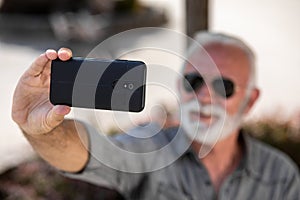 Old man tourist enjoys a vacation and takes a selfie on the street