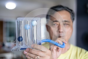 Old man uses a Tri-ball Incentive Spirometer for check his lung function