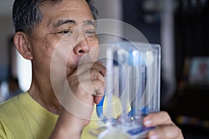 Old man uses a Tri-ball Incentive Spirometer for check his lung function