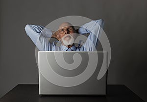 Old man using a laptop. Successful businessman is dreaming