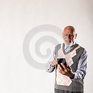 Old man is using a smart phone on gray background with copy space