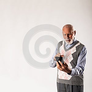 Old man is using a smart phone on gray background with copy space