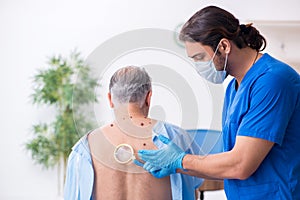 Old man visiting young male doctor dermatologist