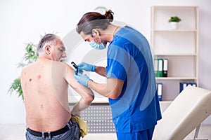 Old man visiting young male doctor dermatologist