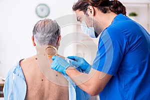 Old man visiting young male doctor dermatologist