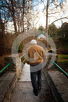 Old Man Walking Across a Bridge Outside