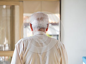 An old man walking away into a bright doorway