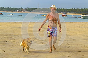 Old Man Walking Forward with his Dog at Beach