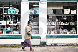 An old man walks alone smoking a pipe