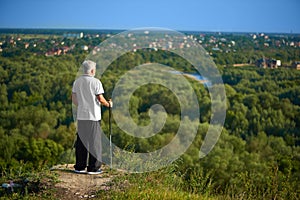 Old man watching beatiful panorame keeping tracking sticks.