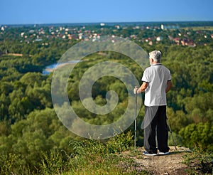 Starý muž sleduje panorama města a drží sledovací hůlky.