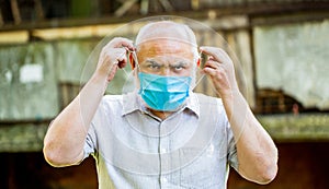 Old man wearing face mask. Portrait of an old man, years old, in a medical mask. Concept danger of coronavirus for the