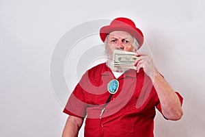 Old man wearing a red derby hat, red shirt and large bolo tie holding up his money and showing off