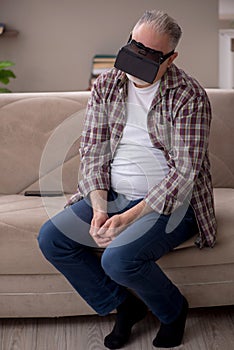 Old man wearing virtual glasses at home