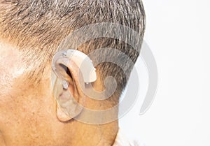 An old man wears a hearing aid