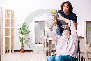 Old man in wheel-chair and young bad caregiver indoors