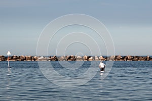 Old man in white t shirt fishing in the Adriatic Sea near Rimini and Riccione