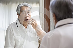 An old man who is anxious about his complexion in the mirror