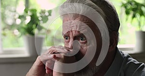 Old man widower mourning seated alone at home closeup view