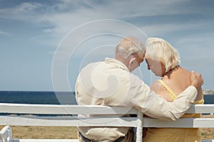 Old man and woman on bench at the sea