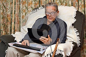 Old man working with laptop computer at home