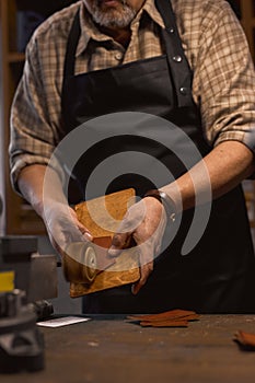 old man working with leather edge grinding machine