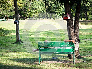 The old man with wrist watch and wearing a white cowboy hat was resting on a green chair in the garden