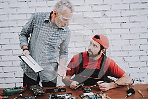 Old Manager Checking Motherboard near Worker.