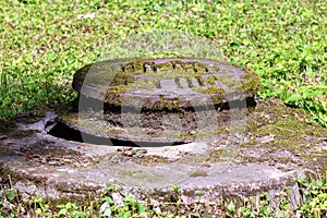 Old manhole cover overgrown with moss