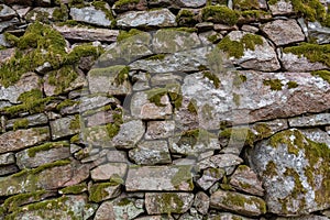 An old manmade stone wall with moss on it