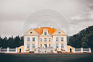 Old manor house in Estonia surrounded by trees against the cloudy sky