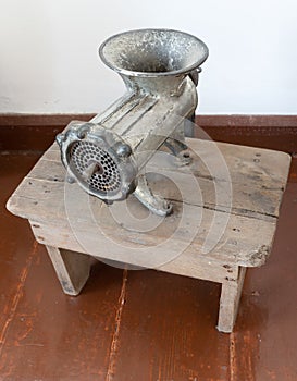 An old manual meat grinder on a wooden table