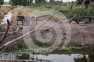 Old manual Power Tiller, a two-wheeled agricultural implement fitted with rotary tillers Parked by groove canal in a plantation photo