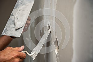 Old manual worker with wall plastering tools renovating house.