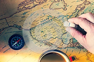 An old map of America with compass, a cup of tea and toy car in hand. Concept of traveling around the country in an old school