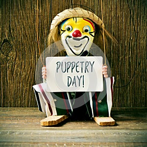 Old marionette with a signboard with the text puppetry day
