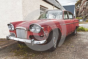 Old maroon car abandoned next to a house